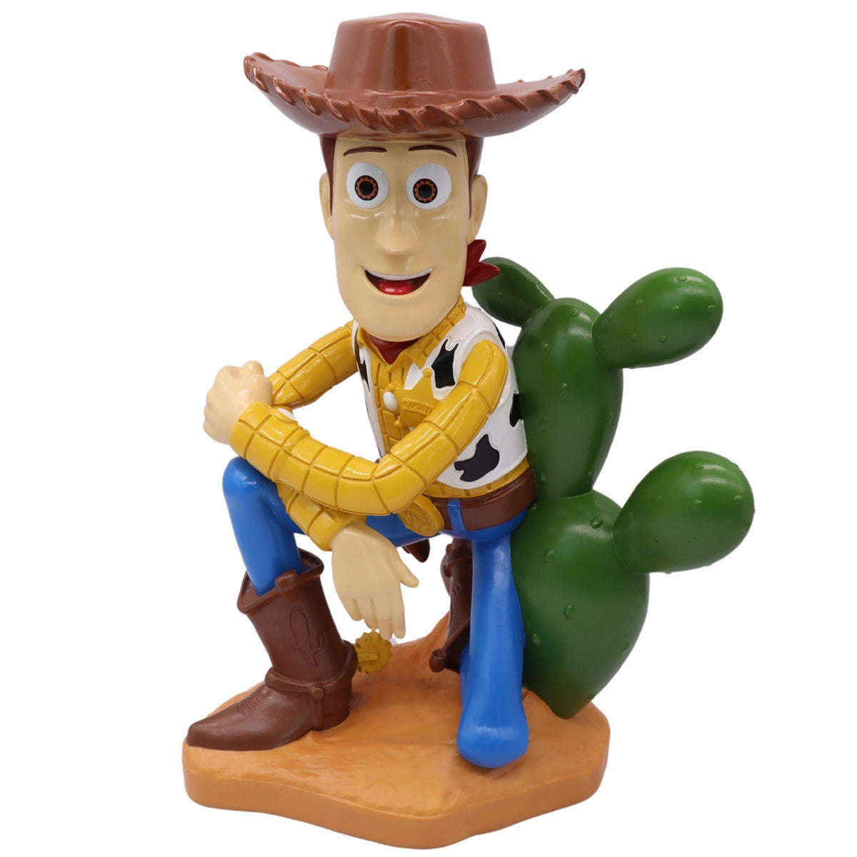 Toy figure of a woody cowboy character sitting next to a cactus on a white background
