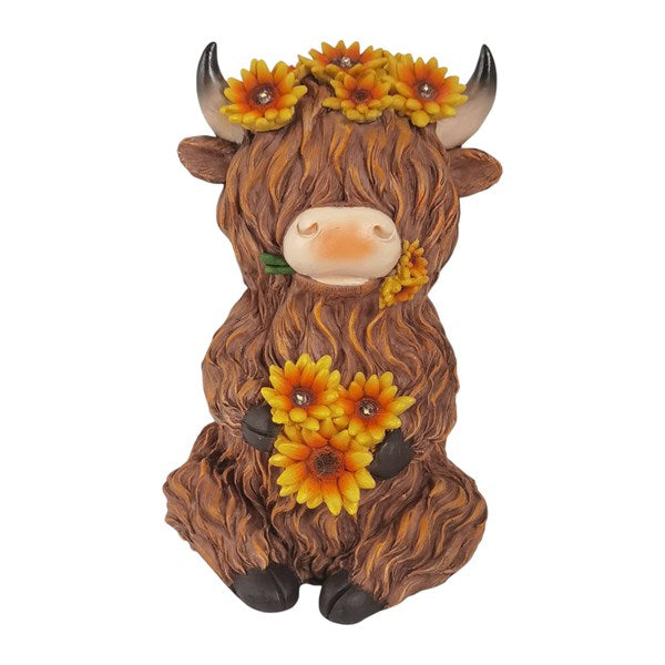 Decorative figurine of a cow with sunflower decorations on a white background